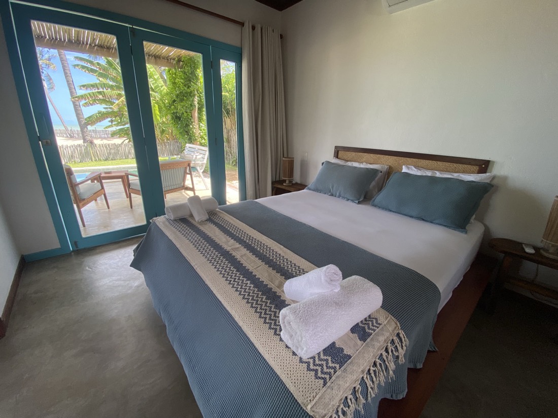 Suíte da Casa Vento com cama queen e porta para a área da piscina